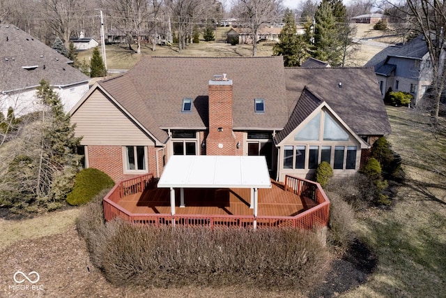 back of property with roof with shingles, a chimney, a deck, and brick siding