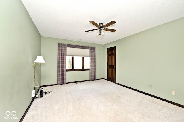 empty room with ceiling fan, light colored carpet, visible vents, and baseboards