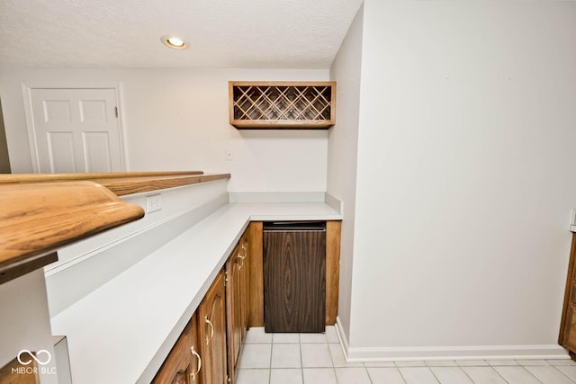 bar with baseboards, light tile patterned flooring, a textured ceiling, a bar, and recessed lighting