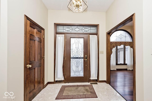 entrance foyer featuring a chandelier, baseboards, and wood finished floors