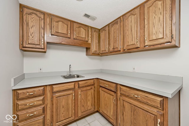 kitchen with brown cabinetry, light countertops, and a sink