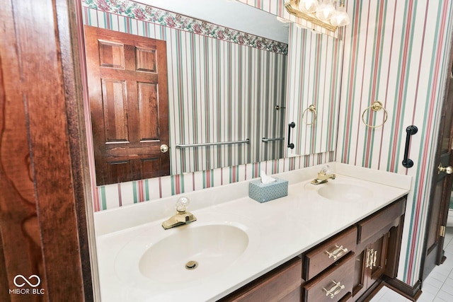 bathroom featuring double vanity, wallpapered walls, tile patterned flooring, and a sink