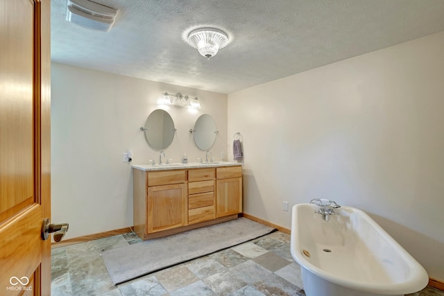 full bathroom featuring double vanity, a sink, baseboards, and a textured ceiling