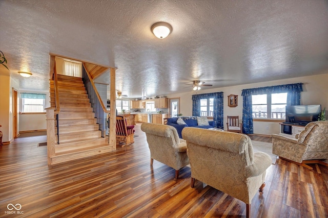 living room with stairs, a textured ceiling, and wood finished floors