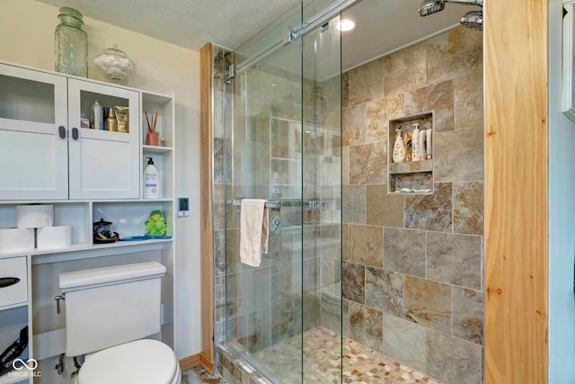 bathroom featuring a shower stall, toilet, and a textured ceiling