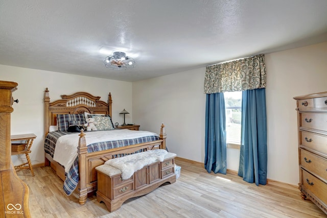 bedroom with a textured ceiling and light wood finished floors