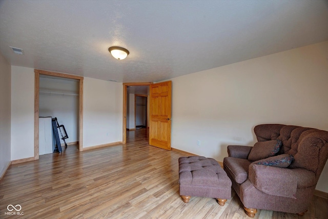 sitting room with light wood-style floors, visible vents, and baseboards