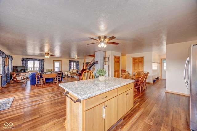 kitchen with light wood-style flooring, a center island, freestanding refrigerator, light countertops, and light brown cabinetry