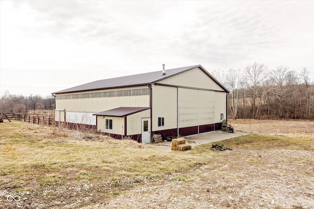 view of property exterior featuring fence, metal roof, a garage, a pole building, and an outdoor structure