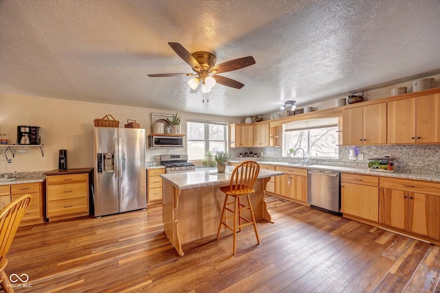 kitchen with light wood-style floors, appliances with stainless steel finishes, backsplash, and a sink