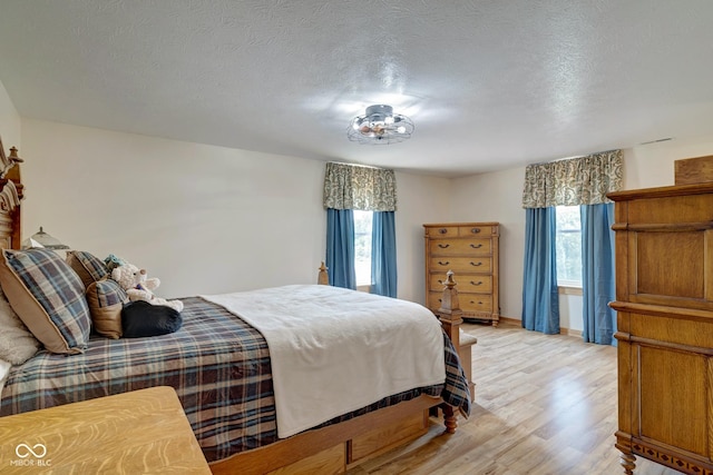 bedroom featuring light wood-type flooring, a textured ceiling, and baseboards