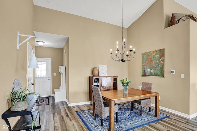 dining room featuring an inviting chandelier, light wood-style floors, baseboards, and high vaulted ceiling