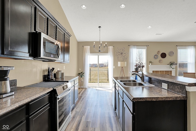 kitchen featuring a sink, dark countertops, stainless steel appliances, light wood-style floors, and dark cabinets