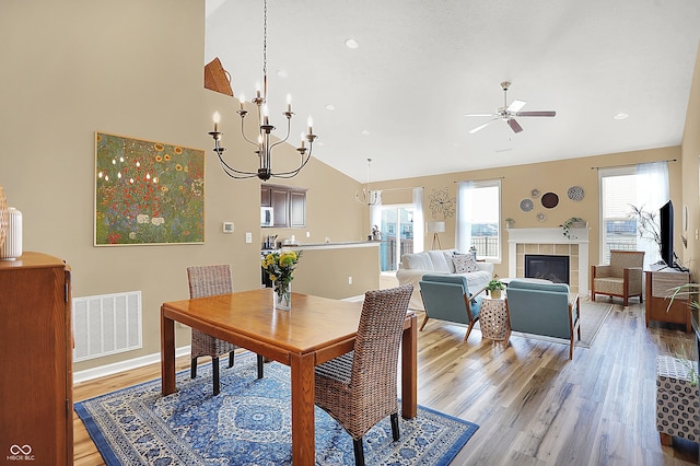 dining room with baseboards, visible vents, lofted ceiling, ceiling fan with notable chandelier, and light wood-type flooring