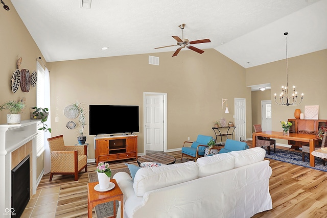 living room with a wealth of natural light, visible vents, ceiling fan with notable chandelier, and a fireplace with flush hearth