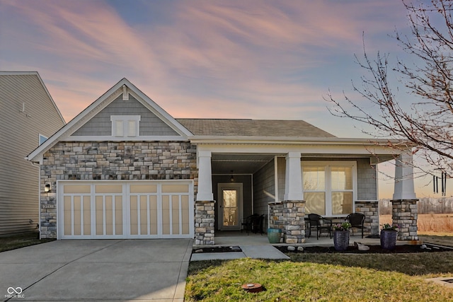 view of front of house featuring stone siding, a porch, concrete driveway, and a garage