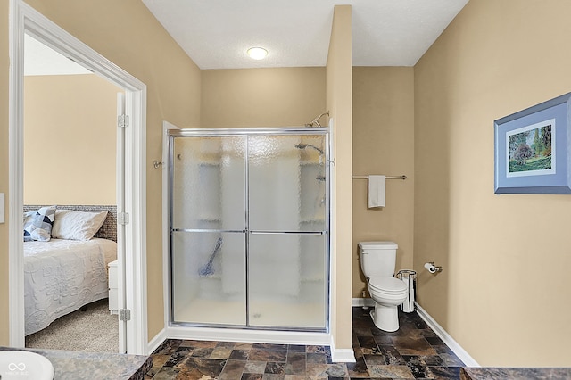 full bath featuring toilet, a stall shower, ensuite bathroom, stone finish floor, and baseboards