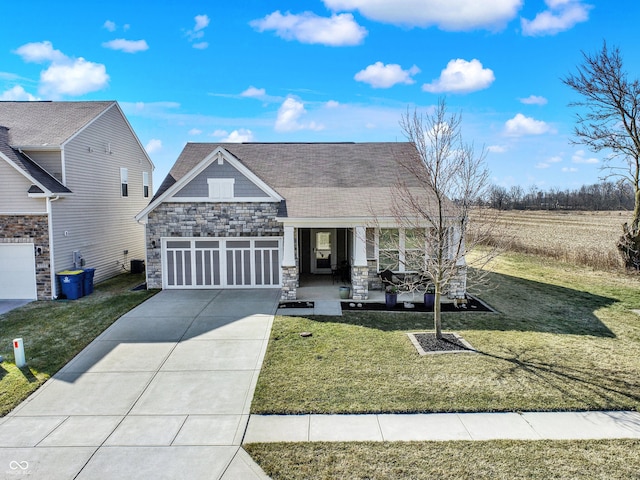 view of front of property with a front lawn, concrete driveway, covered porch, a garage, and stone siding