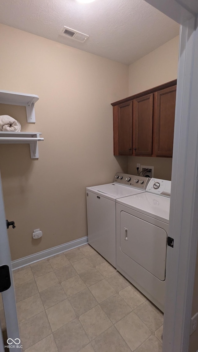 laundry area with a textured ceiling, visible vents, baseboards, cabinet space, and washer and clothes dryer