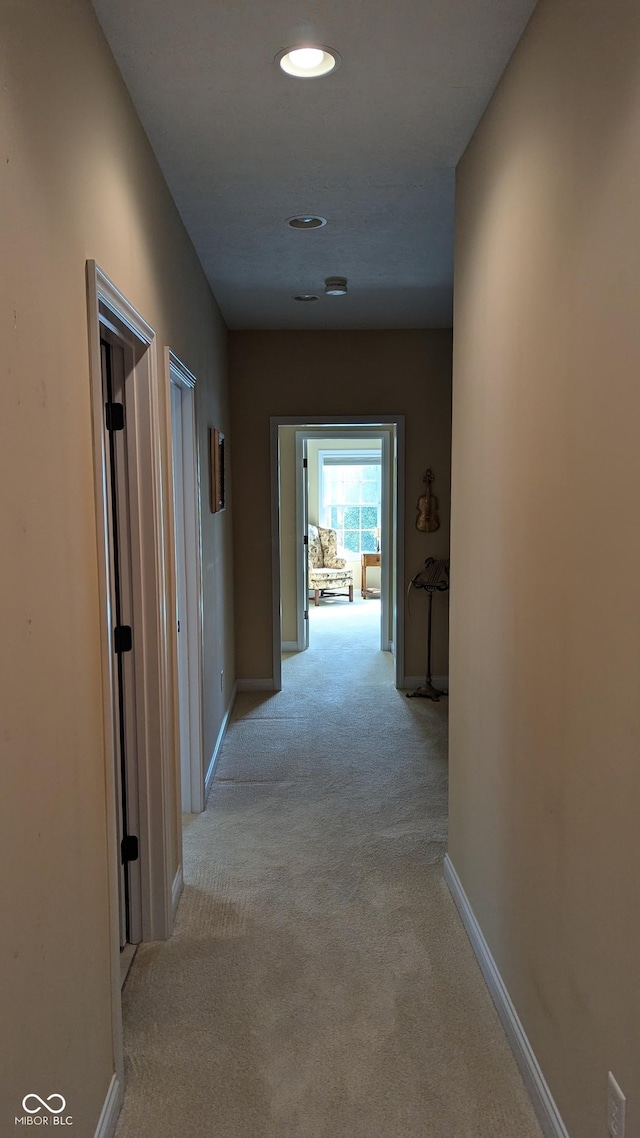 hallway featuring light carpet and baseboards