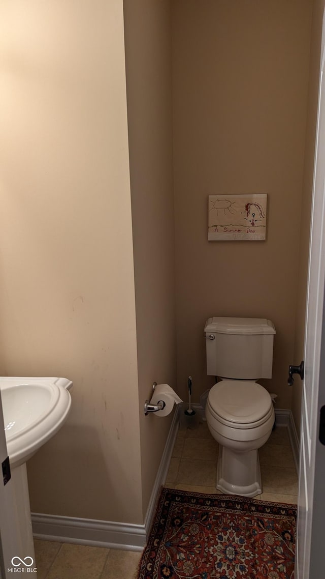 half bath featuring toilet, baseboards, and tile patterned floors