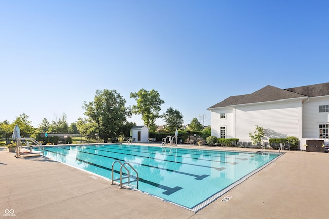 community pool featuring a patio, an outdoor structure, and a shed