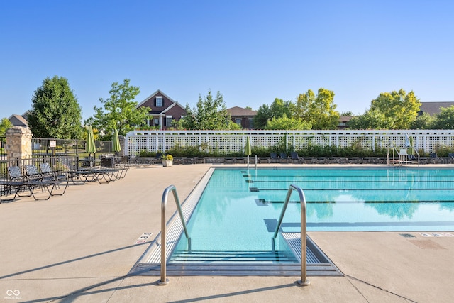 pool with a patio area and fence