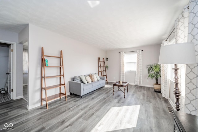 living room featuring baseboards, visible vents, and wood finished floors