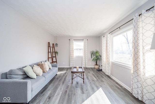 living room featuring wood finished floors, visible vents, and baseboards