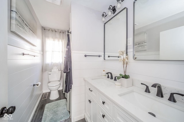 bathroom featuring visible vents, double vanity, a sink, and toilet