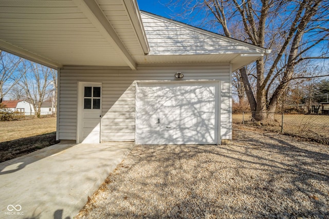 garage featuring driveway and fence