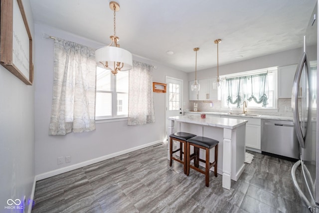 kitchen featuring stainless steel appliances, a center island, white cabinets, and backsplash