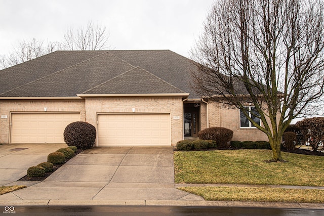 view of front of property with driveway, a shingled roof, an attached garage, a front yard, and brick siding