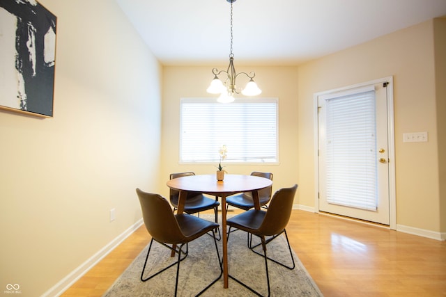 dining space with an inviting chandelier, light wood-style flooring, and baseboards