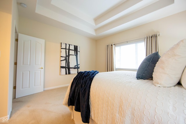carpeted bedroom featuring baseboards and a tray ceiling