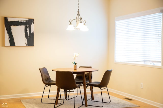 dining area with baseboards, a chandelier, wood finished floors, and visible vents