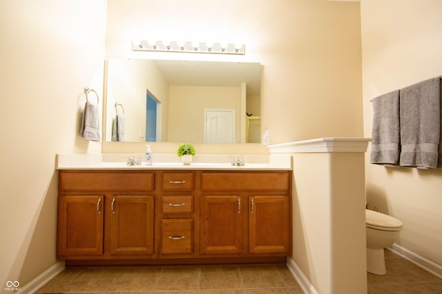 bathroom with double vanity, toilet, baseboards, tile patterned floors, and a sink