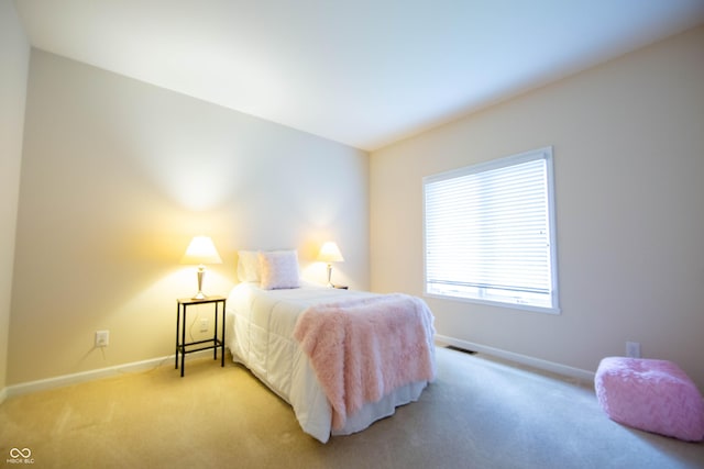 bedroom with baseboards, visible vents, and light carpet