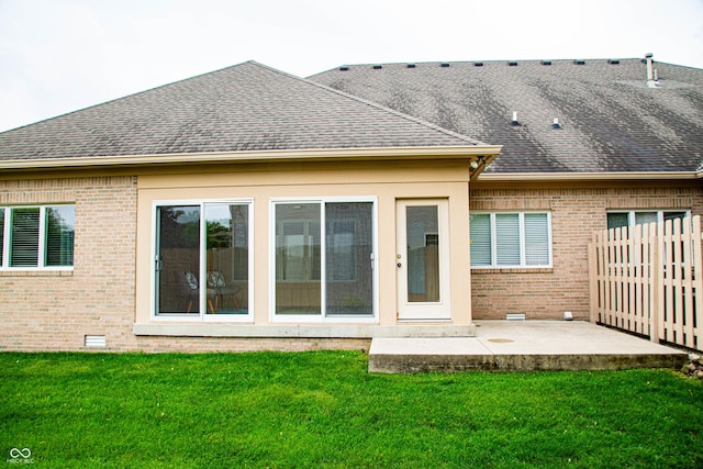 rear view of house with brick siding, a patio area, fence, and a yard