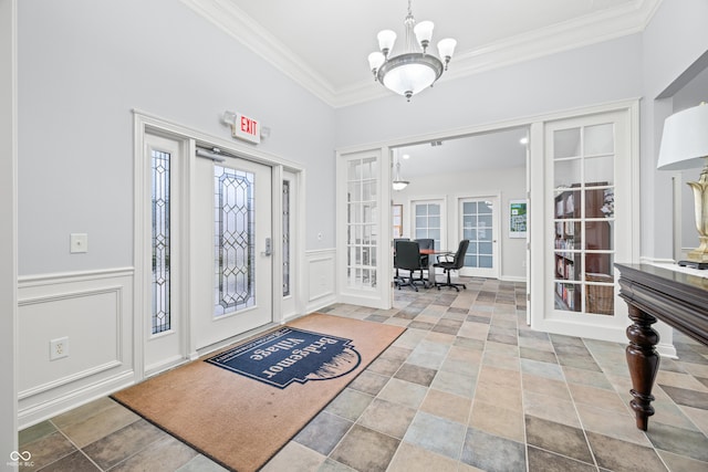 foyer with french doors, a notable chandelier, a decorative wall, ornamental molding, and wainscoting