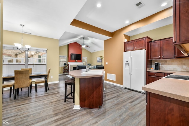 kitchen with white fridge with ice dispenser, light wood-style flooring, light countertops, and visible vents