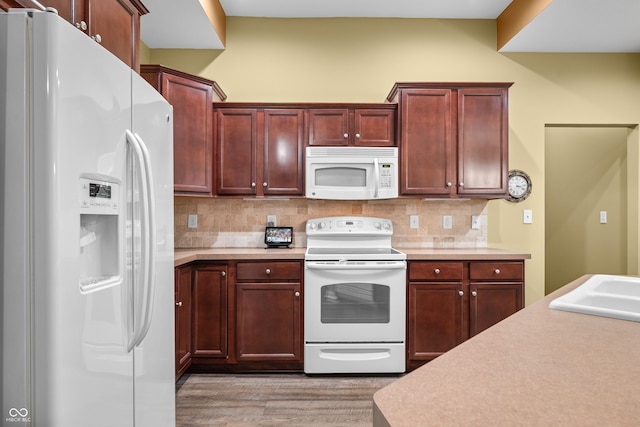 kitchen featuring white appliances, dark brown cabinets, light countertops, and decorative backsplash