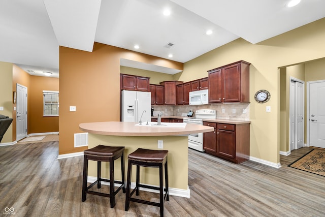 kitchen featuring white appliances, visible vents, light countertops, light wood-type flooring, and backsplash