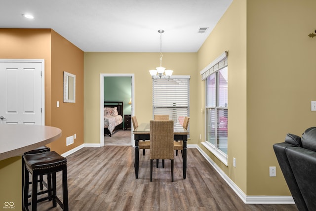 dining area with dark wood-style flooring, visible vents, a notable chandelier, and baseboards