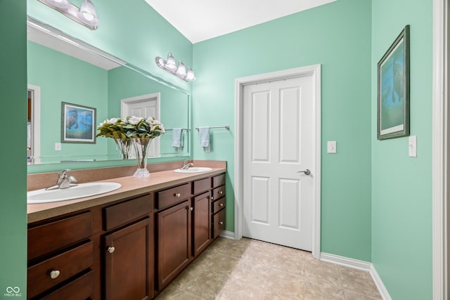 full bath featuring double vanity, baseboards, and a sink