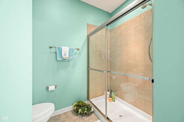 bathroom featuring a stall shower, tile patterned flooring, baseboards, and toilet