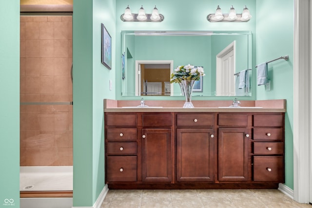 bathroom featuring tile patterned flooring, a sink, a tile shower, and double vanity