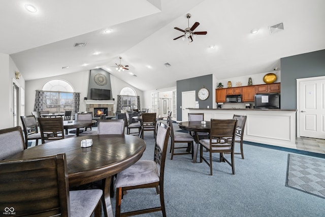 dining room with ceiling fan, a tiled fireplace, and visible vents