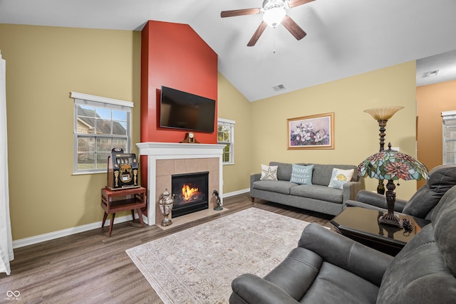 living area with baseboards, a tiled fireplace, visible vents, and wood finished floors