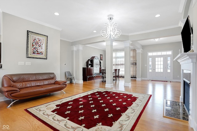 living area with crown molding, decorative columns, baseboards, and wood finished floors